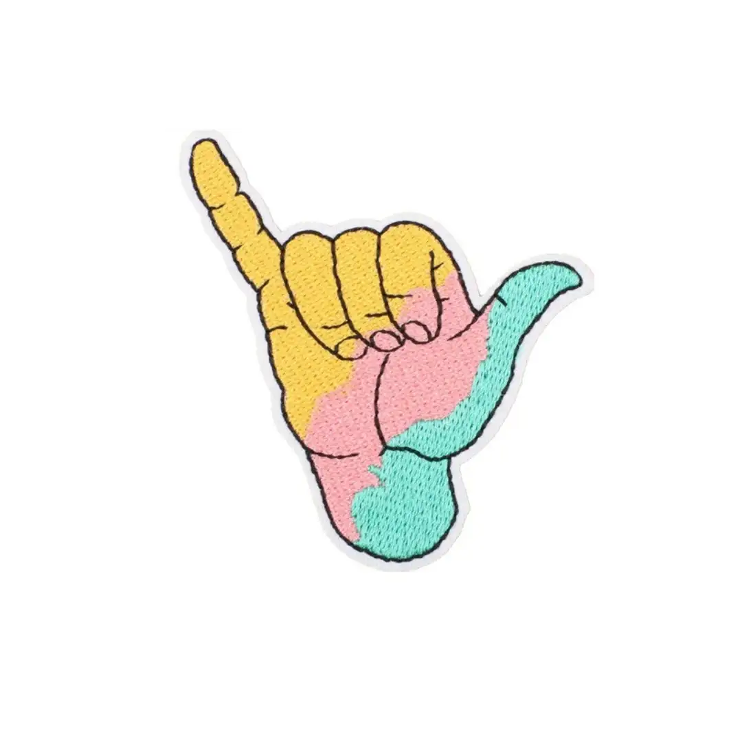 A colorful embroidered patch featuring a hand making the ’shaka’ sign, with yellow on the thumb and index finger, pink across the palm, and teal on the ring and little fingers.
