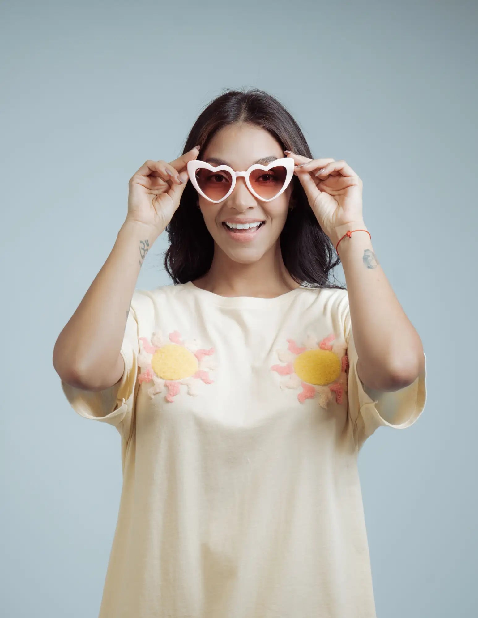 A pair of heart-shaped sunglasses with a white frame and gradient pink to orange lenses.
